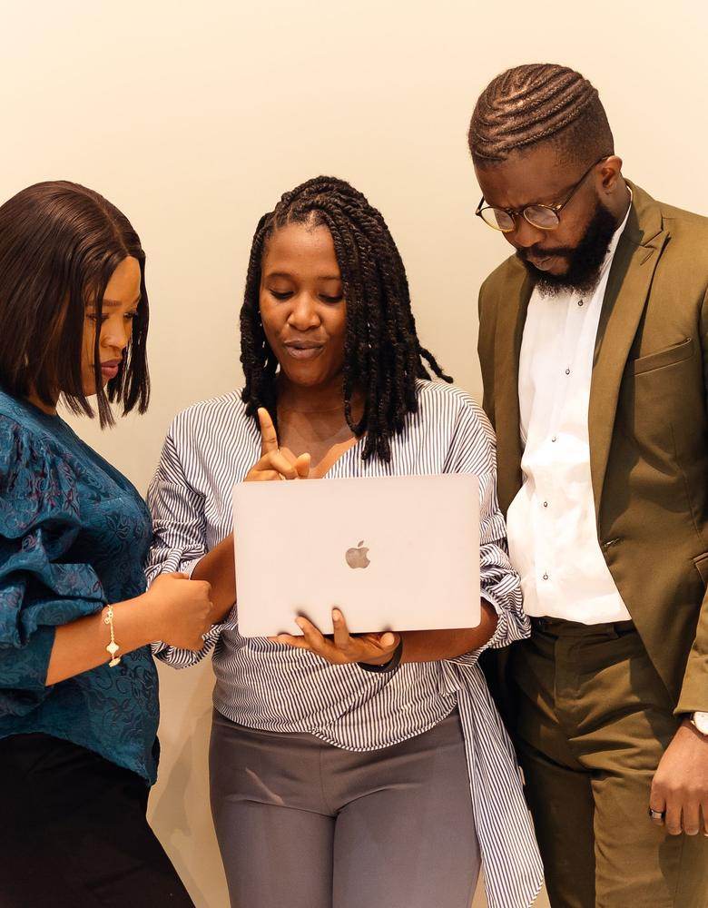 Three colleagues looking together at a laptop in an office